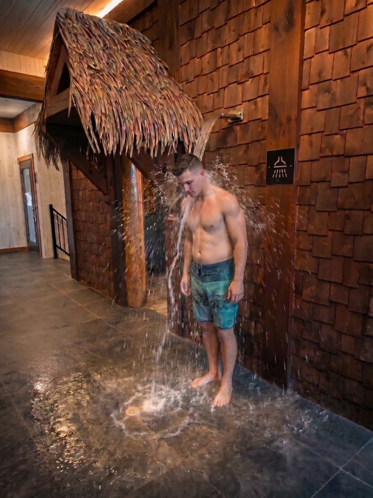 Homme sous douche à seau dans spa rustique