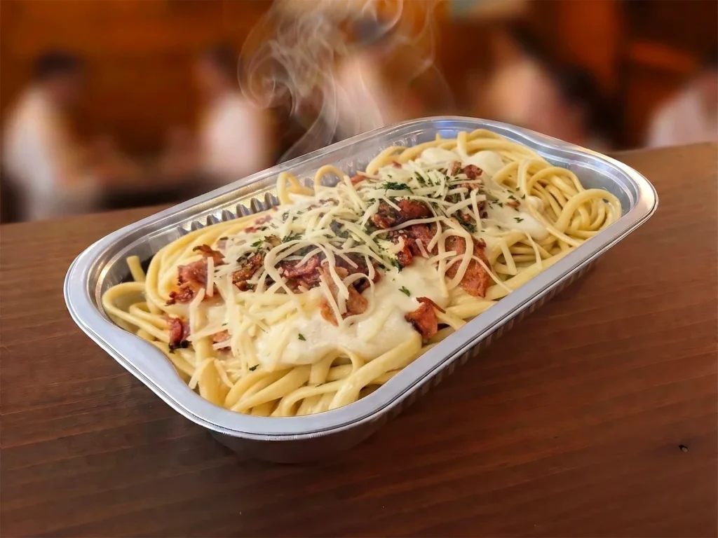Spaghettis crémeux au bacon fumant dans un contenant