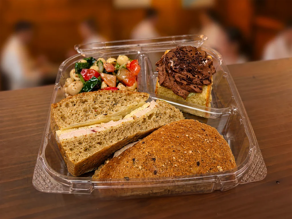 Boîte-repas avec sandwich, salade de pâtes et gâteau au chocolat